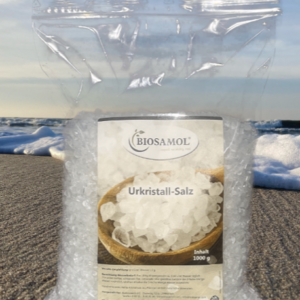 Ein Nachfüllbeutel Ur-Kristallsalz von Biosamol, der vor einer Strand-Meer-Kulisse abgebildet ist